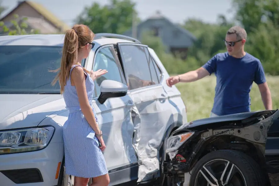 Angry woman and man drivers of heavily damaged vehicles arguing who is guilty in car crash accident on street side. Road safety and insurance concept. How Fault is Determined in Houston Car Accidents