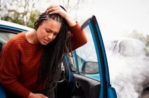 female driver getting out of her car with a car accident concussion